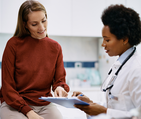 Happy woman going through her medical data with black female doctor at the clinic
