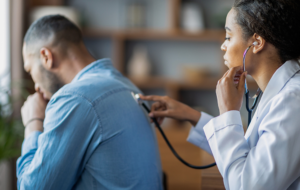general practitioner checking sick man lungs with stethoscope