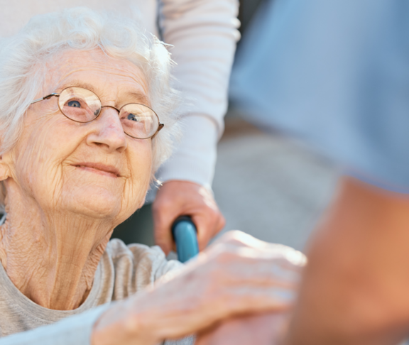 Holding hands, caregiver and senior woman in wheelchair for support outdoor in retirement home. Love, trust and healthcare nurse or medical wellness doctor for disability patient with kindness