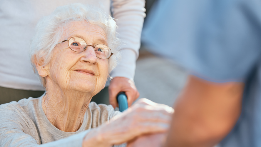 Holding hands, caregiver and senior woman in wheelchair for support outdoor in retirement home. Love, trust and healthcare nurse or medical wellness doctor for disability patient with kindness