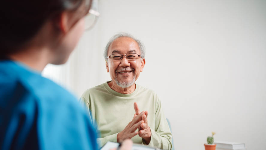 Asian caregiver talking senior male patient checkup in living room at home. Older elderly man consults after physical therapy. Nurse assistance rescue concept